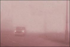 1950s car driving in thick smog. 1950s car driving in thick smog.